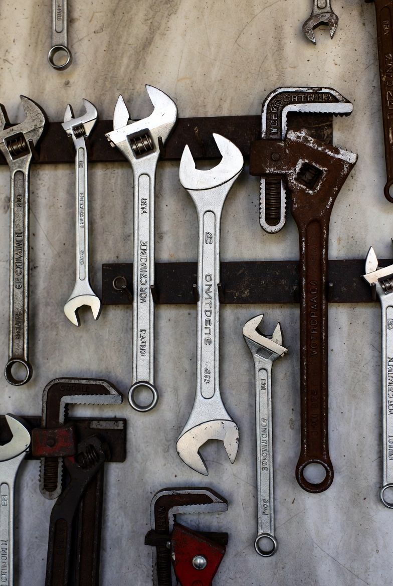 A set of wrenches and tools neatly arranged on a workshop wall — tools like these are classic examples of simple machines